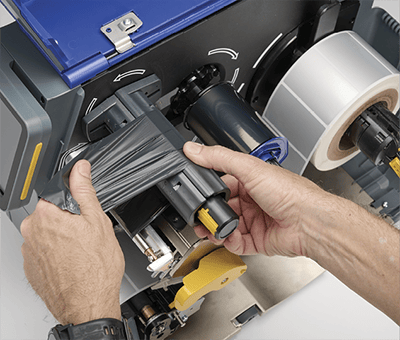 Ein Mitarbeiter legt schnell ein neues Farbband in einen i7500 Drucker ein.