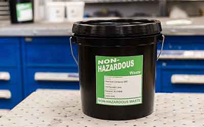 Ein hellgrünes Etikett mit dem Text „Non-Hazardous“ (Ungefährlich) an einem Behälter.