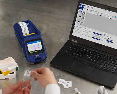 Eine Person bringt ein Etikett, das mit einem M611 gedruckt wurde, in einem Labor auf einem Objektträger an.