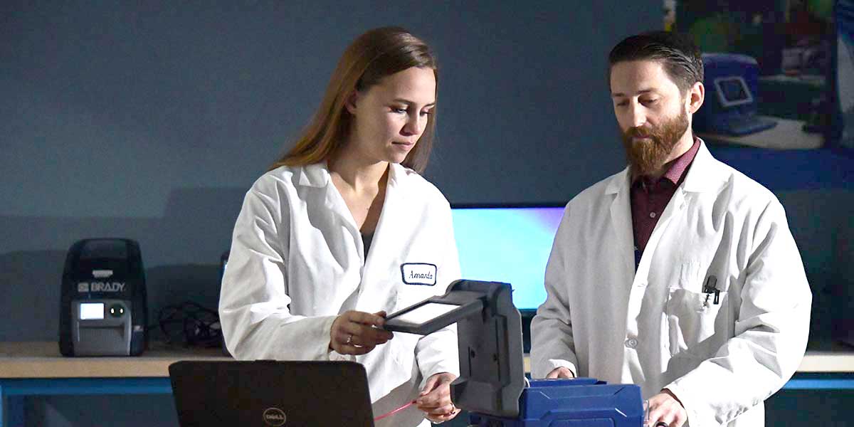 Two engineers inspecting the inside of a printer.