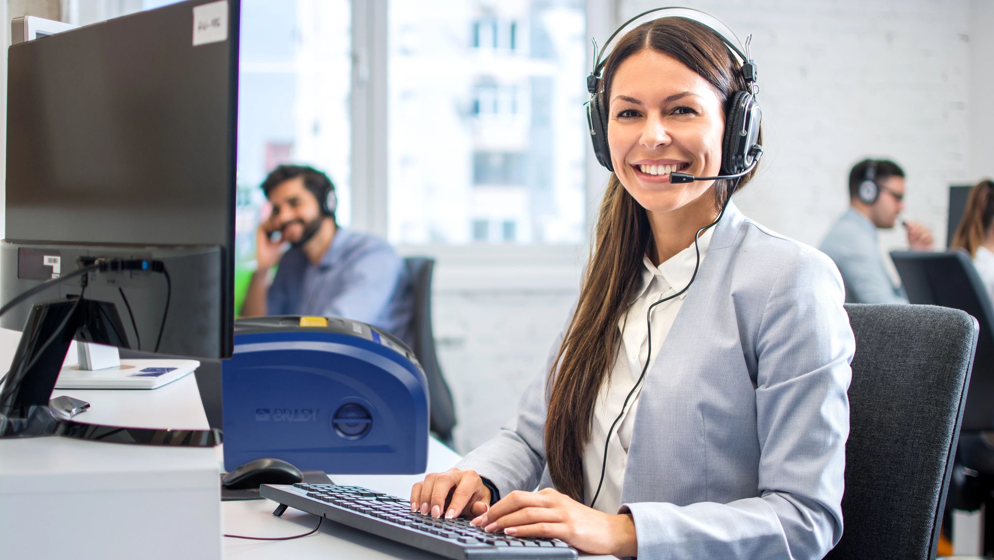 Eine Person hält ein Smartphone. Der Bildschirm des Smartphones zeigt ein hellgelbes Etikett, das mit der mobilen App „Express Labels“ erstellt wurde. Im Hintergrund befindet sich ein Kunststoffbehälter, der mit dem gedruckten Etikett gekennzeichnet ist.